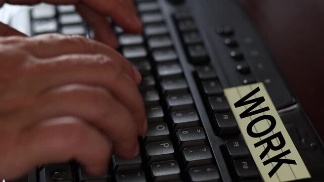 Un primer plano de un teclado de una computadora con las manos de una mujer adulta y una nota amarilla con la palabra trabajando o trabajo