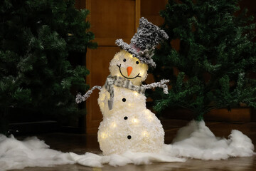 Winter Decor.Big Snowman figure with lights wearing a black tall hat,scarf under the christmas tree