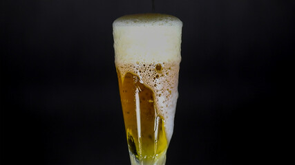 Refreshing Golden Beer with Abundant White Foam Overflowing from a Glass