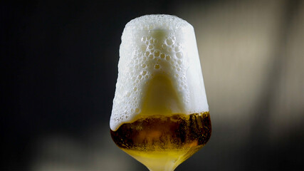 Refreshing Golden Beer with Abundant White Foam Overflowing from a Glass
