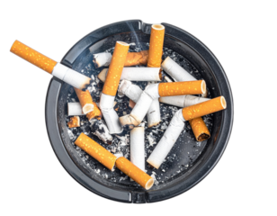 Overhead shot of a filled ashtray, with burnt cigarette butts and wisps of smoke