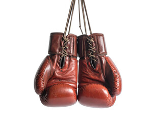 Pair of vintage, worn red leather boxing gloves hanging against a stark black background