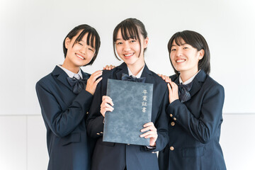 Elementary school and junior high school girls in uniforms and blazers holding graduation certificates