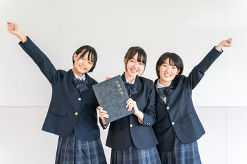 Elementary school and junior high school girls in uniforms and blazers holding graduation certificates