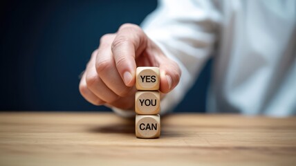 Businessman holding wooden blocks stacked to spell out a powerful motivational message of encouragement and self-belief