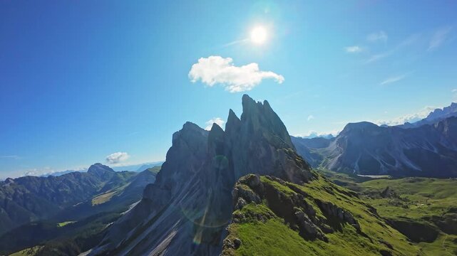 Stunning landscape of Seceda mountain in Dolomites, Italy, captured in bright sunlight with clear skies Dramatic view of Seceda mountain peak in Dolomites, Italy under clear blue sky with sun flare