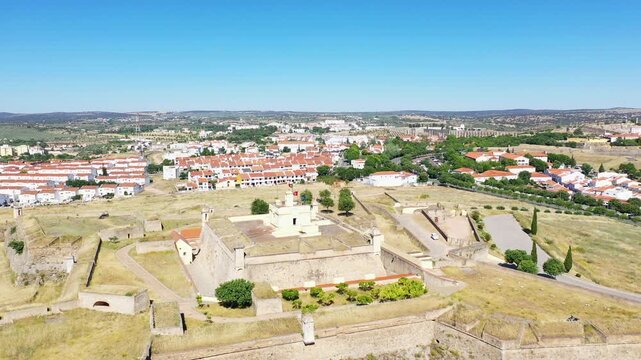 Aerial view of Forte de Santa Luzia, a historic star shaped fortress surrounded by the town of Elvas, Portugal, under a clear blue sky.