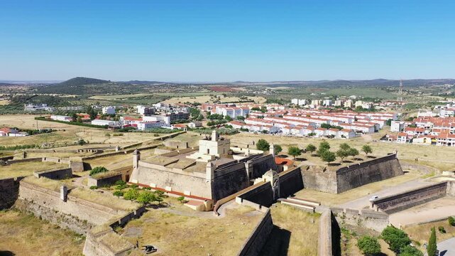Drone shot of the historic Forte de Santa Luzia fortress in Elvas, Portugal, with surrounding town and countryside under a clear blue sky.