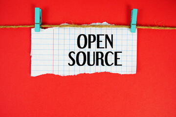 Open Source text written on rip paper with wooden clip on red background