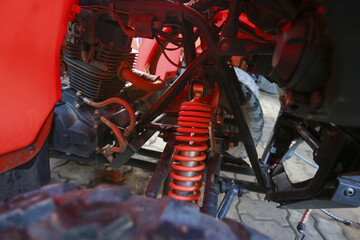 Close up mechanical detail showing robust red suspension spring coil and shock absorber system...