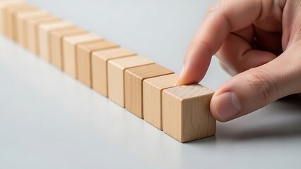 A hand meticulously places the final wooden block into a perfectly aligned sequence, symbolizing the successful completion of a project, strategic planning, and the culmination of a structured process