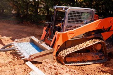 Heavy excavator is working on construction site moving gravel with loader in residential location.