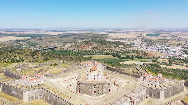 Drone shot of Forte de Nossa Senhora da Graca, a historic star shaped fortress near Elvas, Portugal, surrounded by scenic countryside under a clear blue sky.