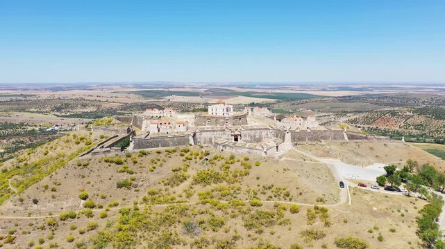Drone shot of Forte de Nossa Senhora da Graca, a historic hilltop fortress near Elvas, Portugal, surrounded by scenic countryside under a clear blue sky.