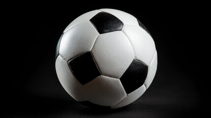 Naklejka premium A close-up studio shot showcases a classic soccer ball on a solid black background, emphasizing its contrasting black and white panels