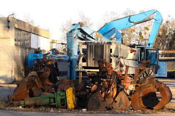 Rusty hydraulic excavator attachments in industrial yard