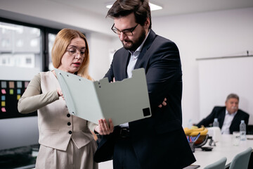 Business colleagues collaborating and reviewing documents during a meeting in a modern office setting