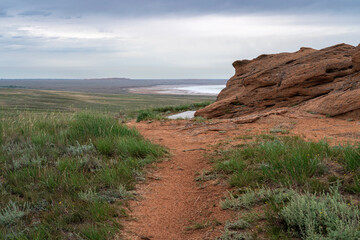 Fancy stones on the slopes of Bolshoe Bogdo Mountain and the salt lake Baskunchak in the distance on a summer day, Bogdinsko-Baskunchak Nature Reserve, Akhtubinsky district, Astrakhan region, Russia