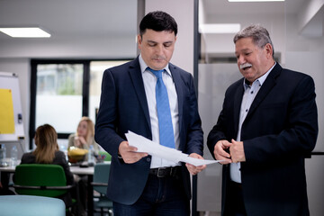 Two business professionals discussing documents in a modern office setting