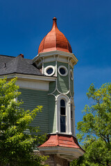 Queen Anne Victorian house: Green turret, red roof, blue sky.