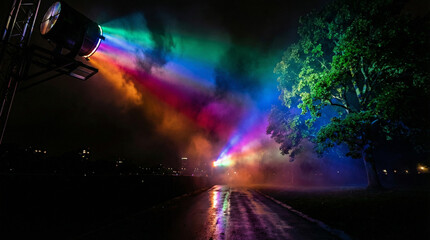 Vibrant rainbow light beams shine through fog at night