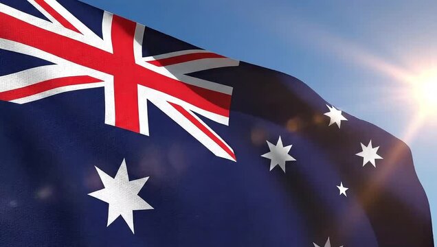 The australian flag waving in the wind with a bright sun shining in the background on a clear blue sky day