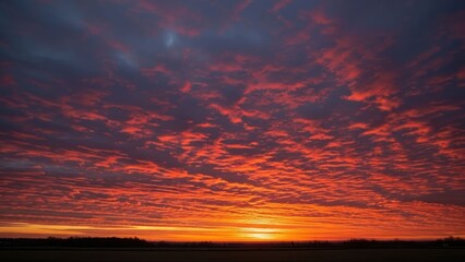 Fiery red and orange clouds fill the sky over a darkened horizon