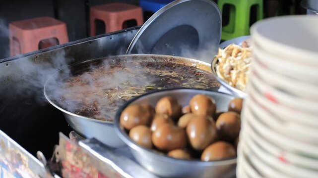 The video background shows Tawan cooking over a charcoal stove, the aroma enticing and delicious, the kind of noodle soup or kway chap commonly sold in tourist areas.