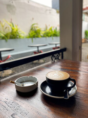 Obraz premium Cup of coffee latte and cigarette on white ashtray 