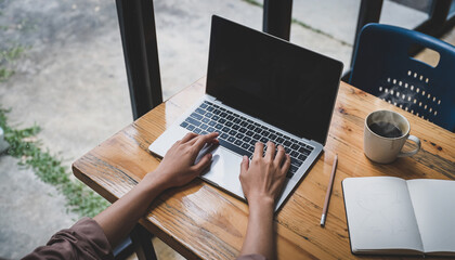 Hands Typing on Laptop Computer at Wooden Desk with Coffee in Modern Workspace