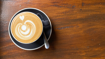 A cup of coffee with latte art on a wooden table in a cafe