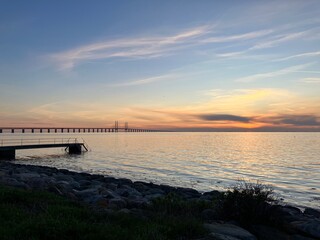 Obraz premium Sunset landscape of the Öresund Bridge from Malmö, Sweden — famous Nordic landmark glowing under colorful twilight sky