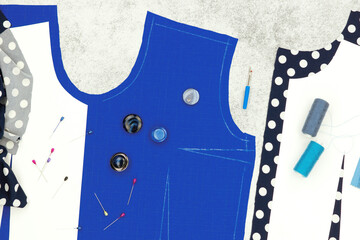 Sewing clothes. Blue fabric, paper pattern, sewing accessories on a textured background. The process of sewing and modeling a dress and blouse.