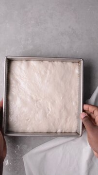 overhead view of focaccia dough proofing in baking pan, top view of a high hydration focaccia bread dough resting in a pan, process of making high hydration focaccia