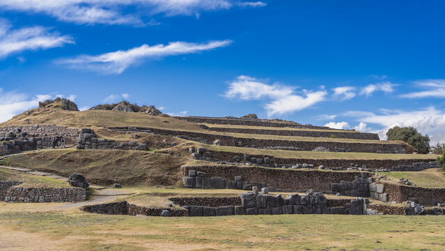 Ruins of the ancient Inca fortress Sacsayhuaman. Stepped terraces on the hillside. Polygonal ashlar masonry. Blue sky, clouds.Peru. Cusco