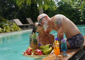 A man and woman with cocktails in a swimming pool