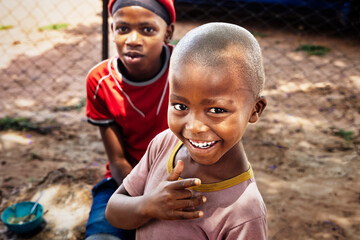 Two happy young boys in rural Botswana with a bowl of food. Great for themes of childhood development, nutrition, and community projects.