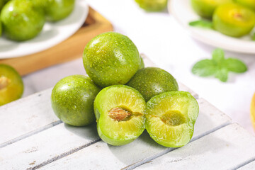 Fresh Green Chinese Plums with Pit on White Wood Surface