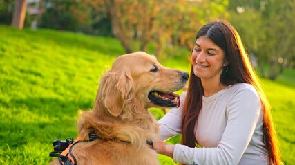 Woman smiling and petting a golden retriever dog in park