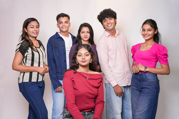 Obraz premium Group of young indian gen z friends standing together on a white background looking at camera.