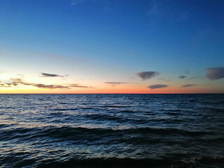Sunset over the sea, the sun sets into the clouds behind the horizon
