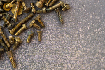Brass screws on a gray background.Vintage bolts with nuts for mounting.An old tool.