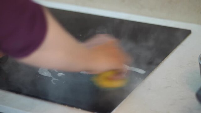 Cleaning a stovetop in the kitchen during morning hours