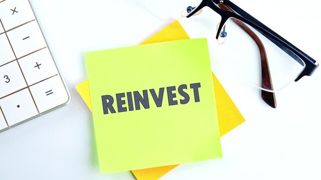 The appearance of the concept word REINVEST on the green sticker. Business and reinvest concept.