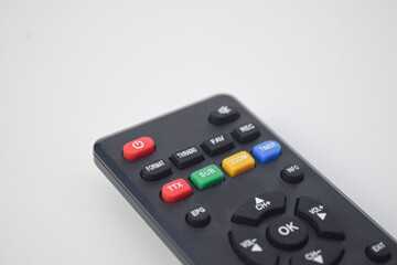 Angled macro shot of colorful buttons on a black remote control, highlighting the power and menu keys