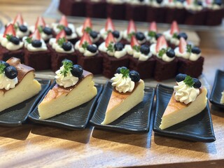 Sliced cheesecake served on plates with whipped cream blueberries and strawberries creating an elegant dessert buffet presentation