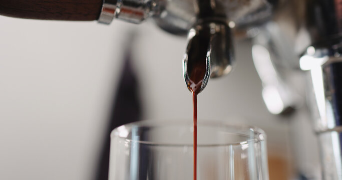 Low angle shot of espresso pour from coffee machine ingo glass cup