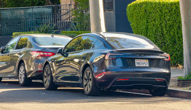 LOS ANGELES, CA - April 4, 2025: Tesla Model 3 parked on a sunny city street.