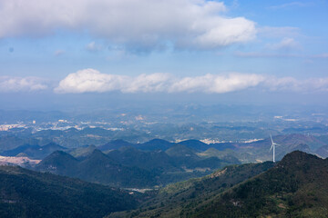 Naklejka premium Wind Turbine on Hilltop with Mountain Scenery and Clouds