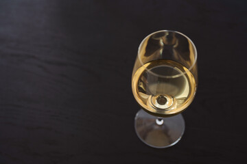 White wine in a wineglass on black oak table with copy space